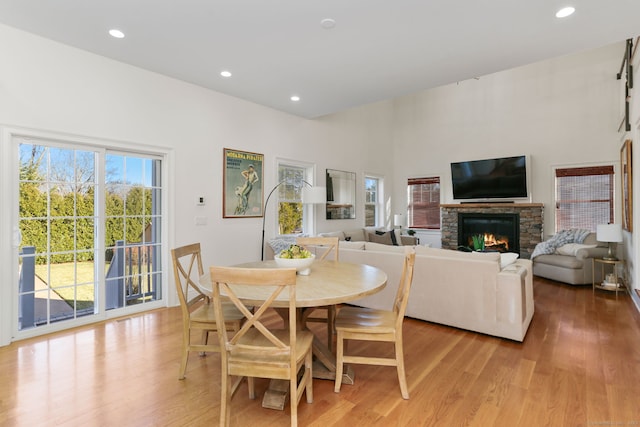 dining area featuring light wood finished floors, a stone fireplace, and a healthy amount of sunlight