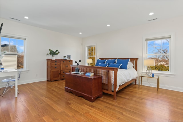 bedroom featuring visible vents, multiple windows, baseboards, and light wood-style flooring