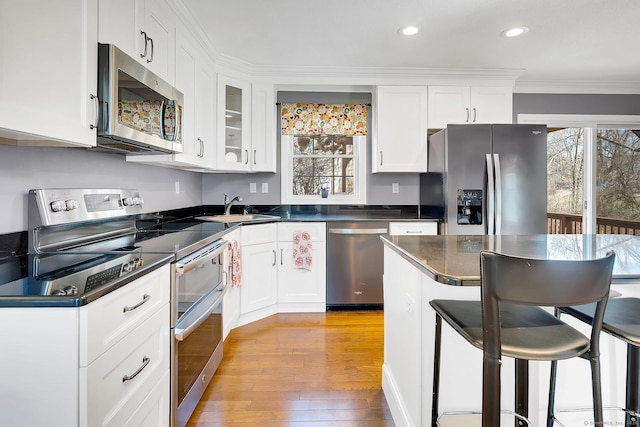 kitchen with dark countertops, appliances with stainless steel finishes, white cabinetry, and a sink