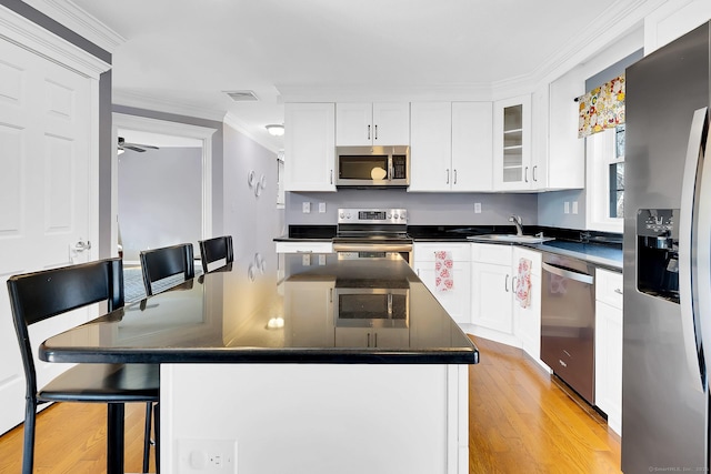 kitchen with dark countertops, visible vents, crown molding, stainless steel appliances, and a sink