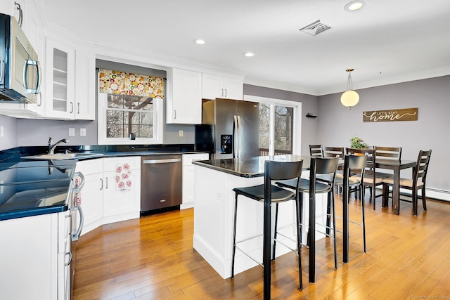 kitchen featuring light wood finished floors, visible vents, appliances with stainless steel finishes, white cabinets, and a sink