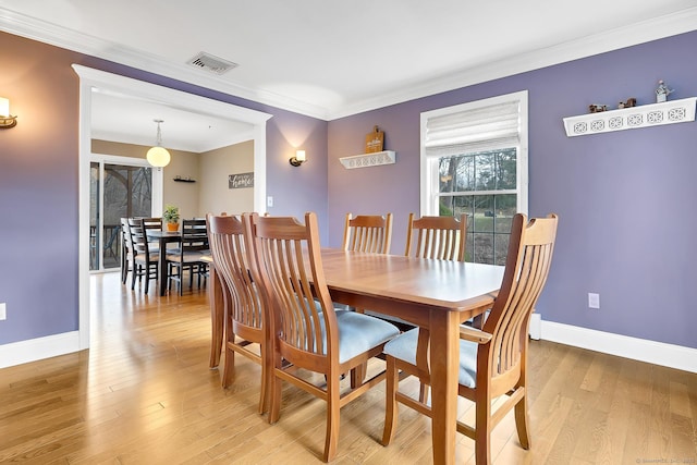 dining area featuring light wood finished floors, visible vents, baseboards, and ornamental molding