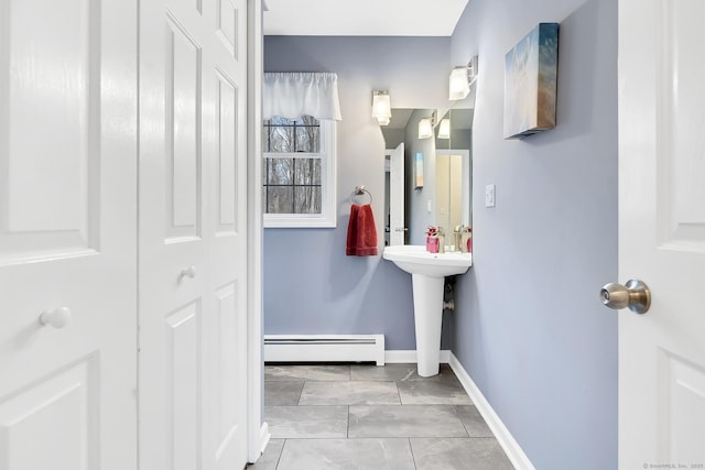 bathroom featuring a sink, a baseboard heating unit, and baseboards