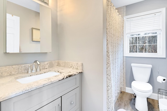 bathroom featuring baseboards, toilet, wood finished floors, and vanity