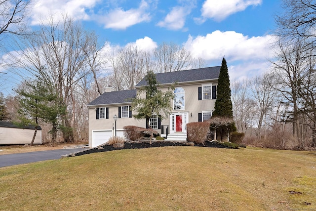 view of front of home with aphalt driveway, a front lawn, a garage, and a chimney