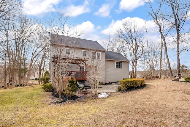 back of house featuring a chimney, a pergola, and a yard