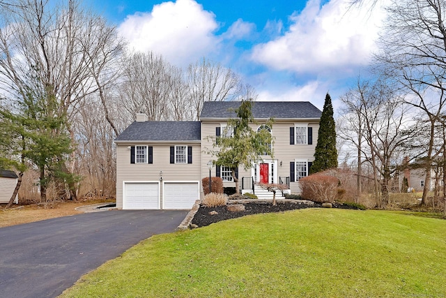 view of front of house featuring a shingled roof, a front yard, a chimney, a garage, and driveway