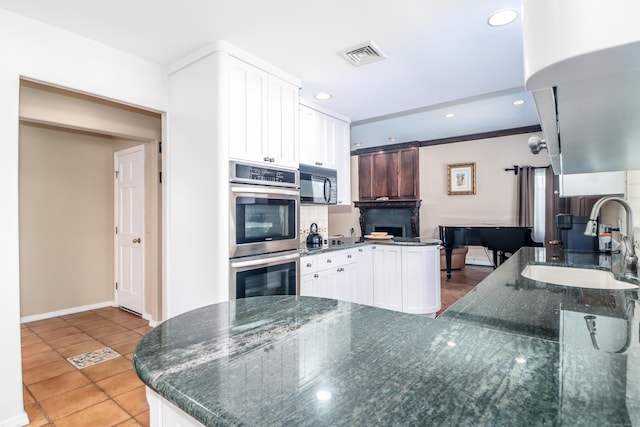 kitchen with visible vents, black microwave, double oven, a peninsula, and a sink