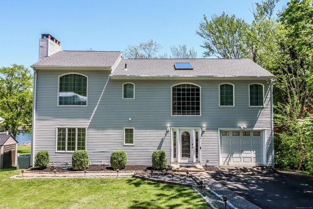 38 N Lake Shore Dr, Brookfield, CT 06804 - back of property with a chimney, asphalt driveway, a yard, an attached garage, and a shingled roof