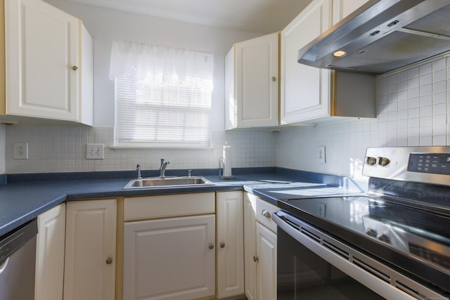 kitchen with a sink, dark countertops, range hood, appliances with stainless steel finishes, and white cabinets