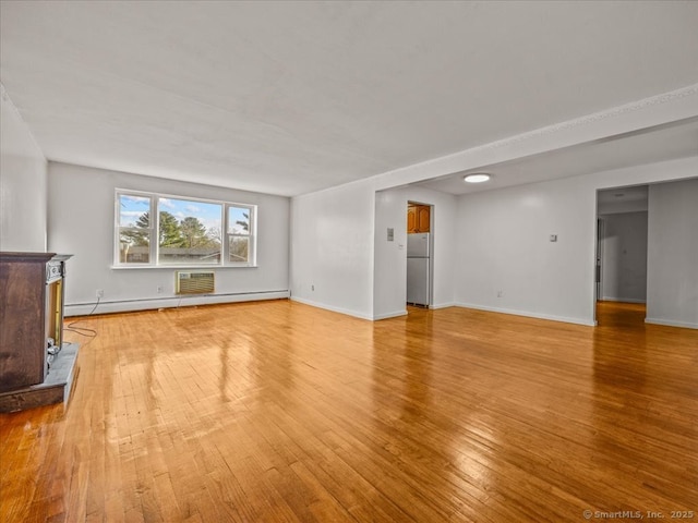 unfurnished living room with baseboards, baseboard heating, light wood-style flooring, and a wall unit AC