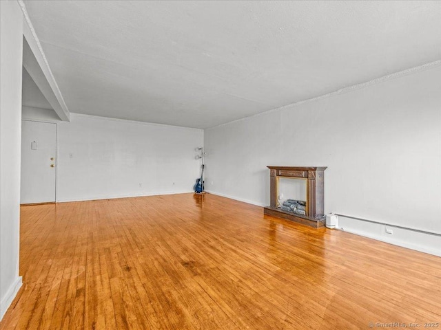 unfurnished living room featuring hardwood / wood-style floors, a fireplace with raised hearth, and a baseboard radiator