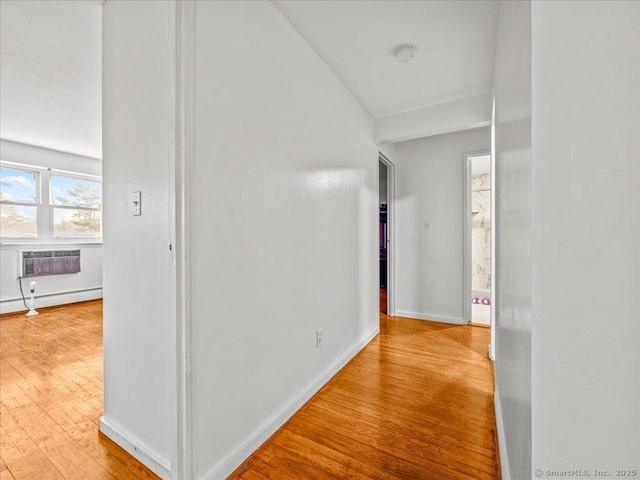 hallway with a wall mounted air conditioner, baseboards, and wood finished floors