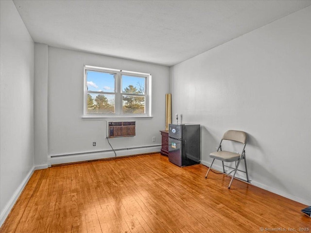 misc room with light wood-style flooring, a wall mounted air conditioner, baseboards, and a baseboard radiator