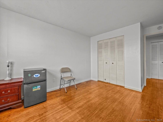 interior space with a closet, baseboards, freestanding refrigerator, and light wood-style floors