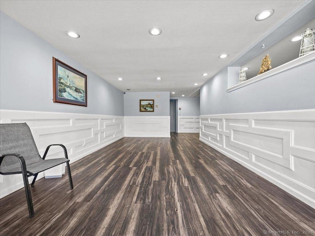 below grade area with recessed lighting, a textured ceiling, wood finished floors, and wainscoting