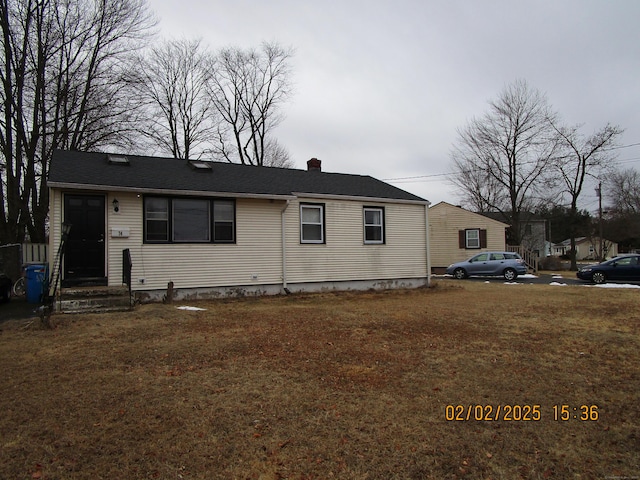 view of front facade with a front yard and a chimney