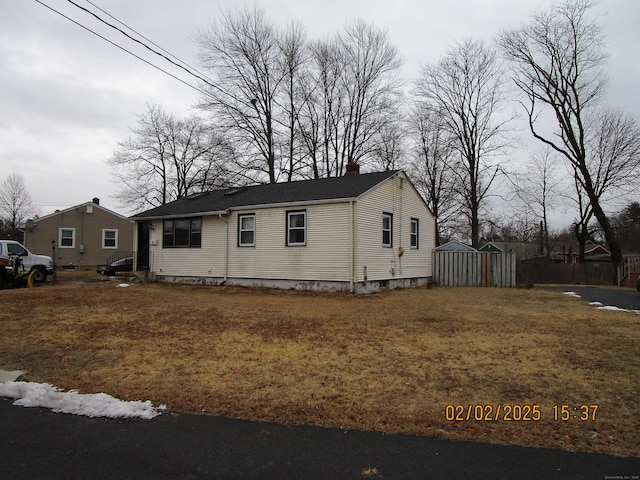 view of front of home with a chimney, an outdoor structure, and a front yard