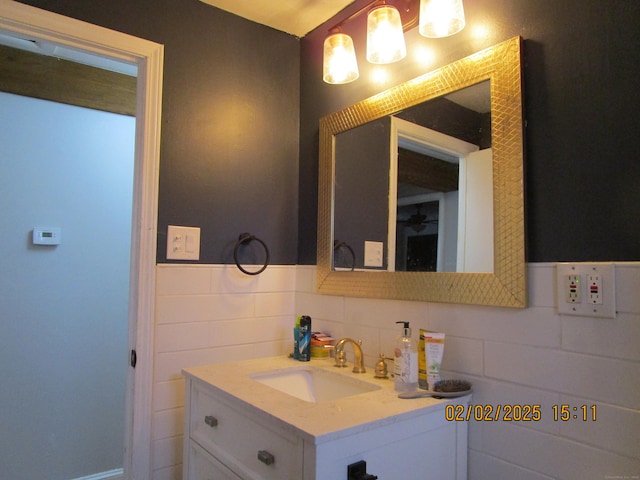 bathroom featuring a wainscoted wall, vanity, and tile walls