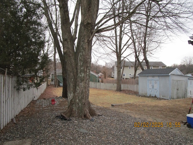 view of yard with an outdoor structure, a fenced backyard, and a shed