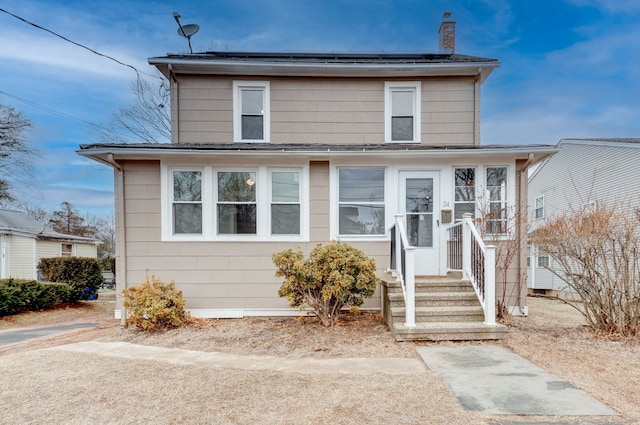 american foursquare style home featuring roof mounted solar panels and a chimney