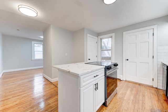 kitchen featuring baseboards, light wood-type flooring, light stone counters, stainless steel range with electric stovetop, and white cabinetry