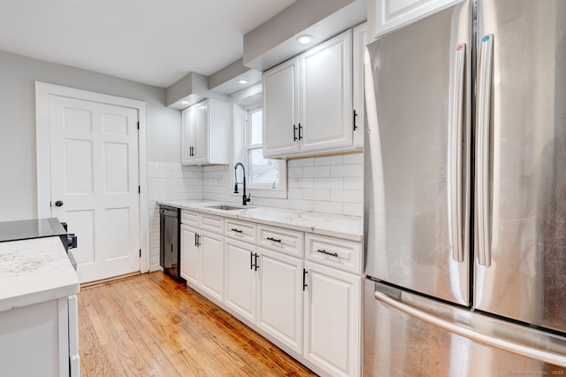 kitchen featuring dishwasher, freestanding refrigerator, light wood-style floors, white cabinetry, and a sink