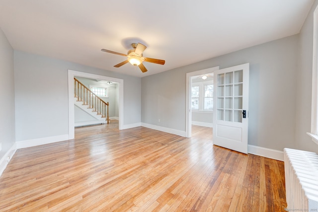 unfurnished living room featuring light wood finished floors, ceiling fan, radiator, and baseboards