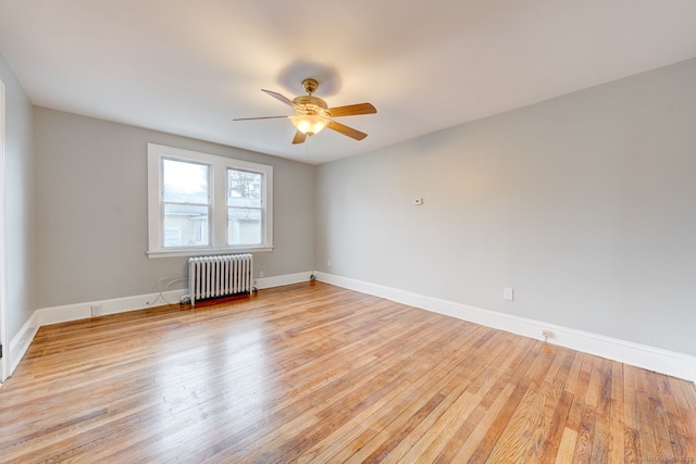 unfurnished room featuring light wood-style flooring, radiator, and baseboards