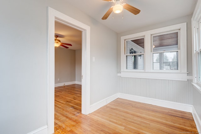 empty room with baseboards, light wood finished floors, and ceiling fan