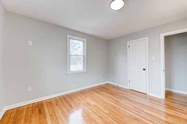 unfurnished room with light wood-type flooring and baseboards