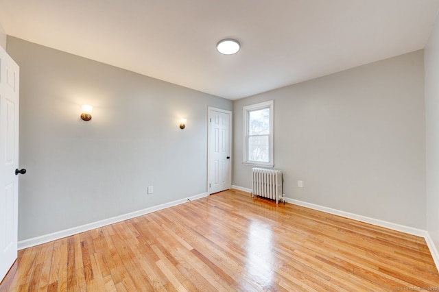 spare room featuring light wood-style flooring, radiator heating unit, and baseboards