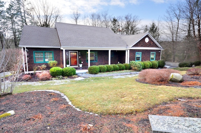 view of front of home with a front yard, covered porch, and a shingled roof