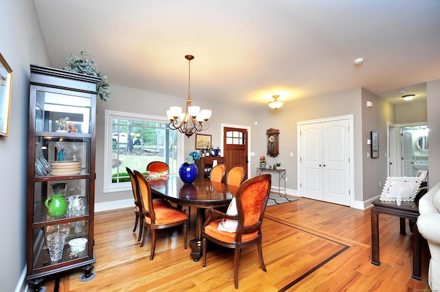 dining room with a chandelier, light wood-type flooring, and baseboards