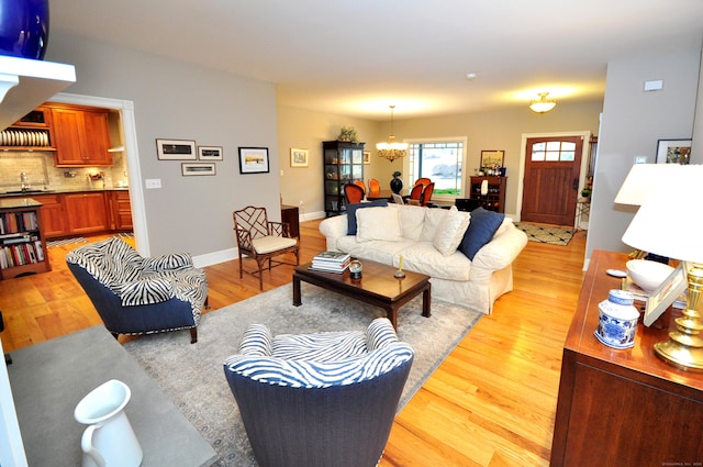 living area with a notable chandelier, baseboards, and light wood-style floors