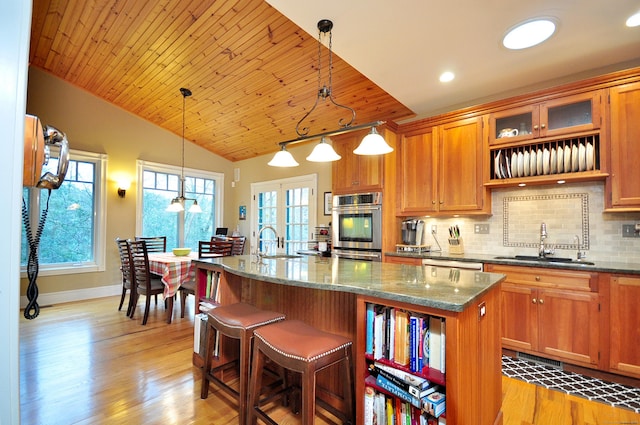 kitchen featuring lofted ceiling, a kitchen island with sink, backsplash, and a sink