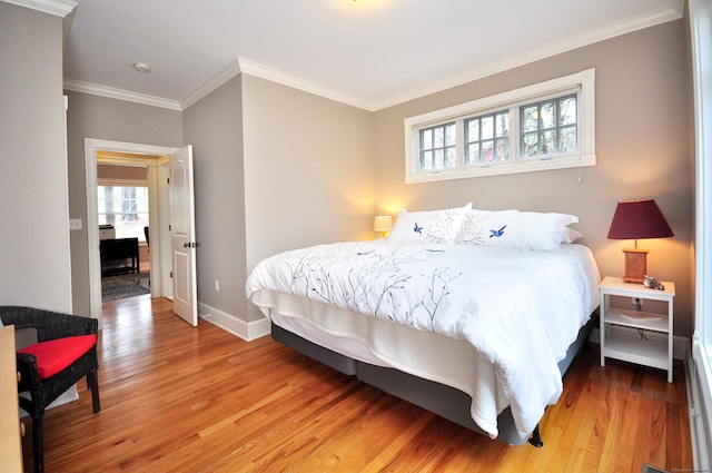 bedroom featuring multiple windows, light wood-type flooring, and baseboards