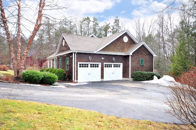 view of side of home with aphalt driveway, roof with shingles, and an attached garage