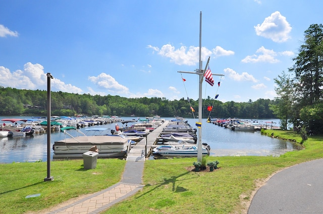 view of dock with a forest view, a yard, and a water view