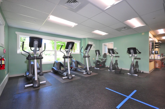 gym featuring baseboards, visible vents, and a paneled ceiling