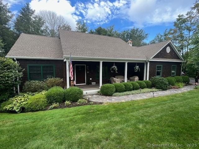 back of house with a lawn and a shingled roof