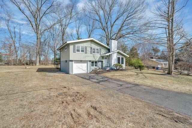 view of front of home with an attached garage, fence, driveway, and a chimney