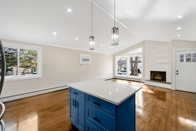 kitchen with vaulted ceiling, blue cabinetry, wood finished floors, and baseboard heating