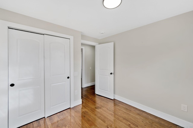 unfurnished bedroom featuring a closet, baseboards, and light wood-style flooring