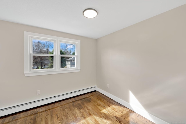 spare room featuring wood finished floors, baseboards, and a baseboard radiator