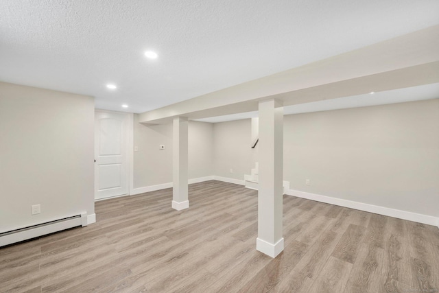 finished basement featuring light wood finished floors, a textured ceiling, stairs, and baseboards