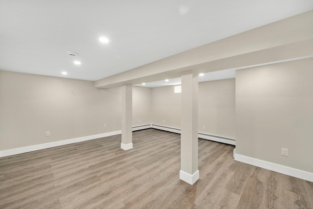 basement featuring baseboard heating, recessed lighting, baseboards, and light wood-style floors