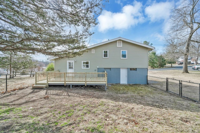 rear view of house featuring a wooden deck, fence, and a gate