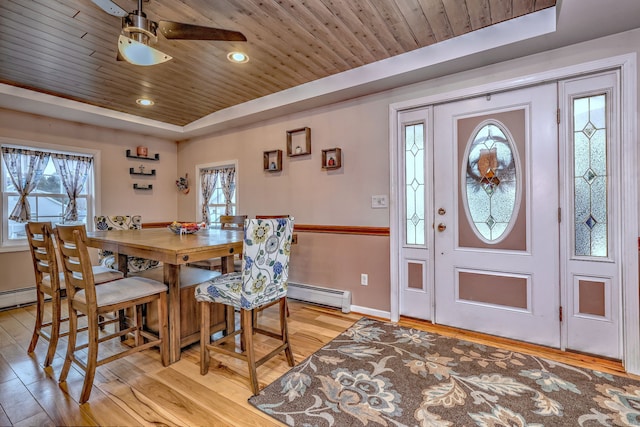 dining space with a raised ceiling, light wood finished floors, baseboards, and wooden ceiling