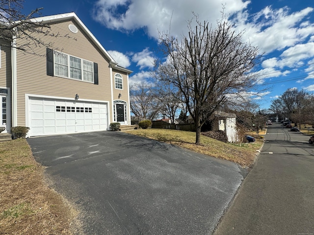 view of side of home featuring aphalt driveway and a garage